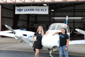 women posing in front of a plane