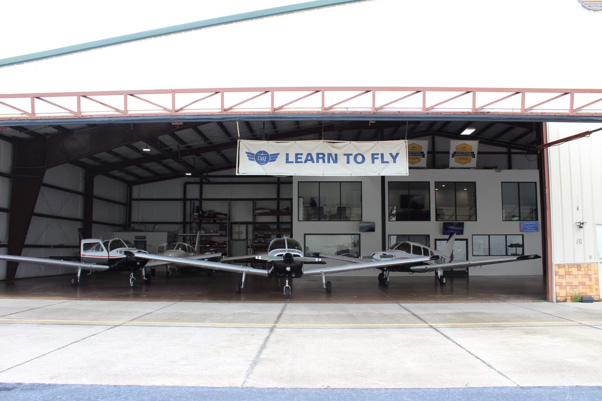 D&J Aviation hangar with training aircraft lined up under a Learn to Fly banner
